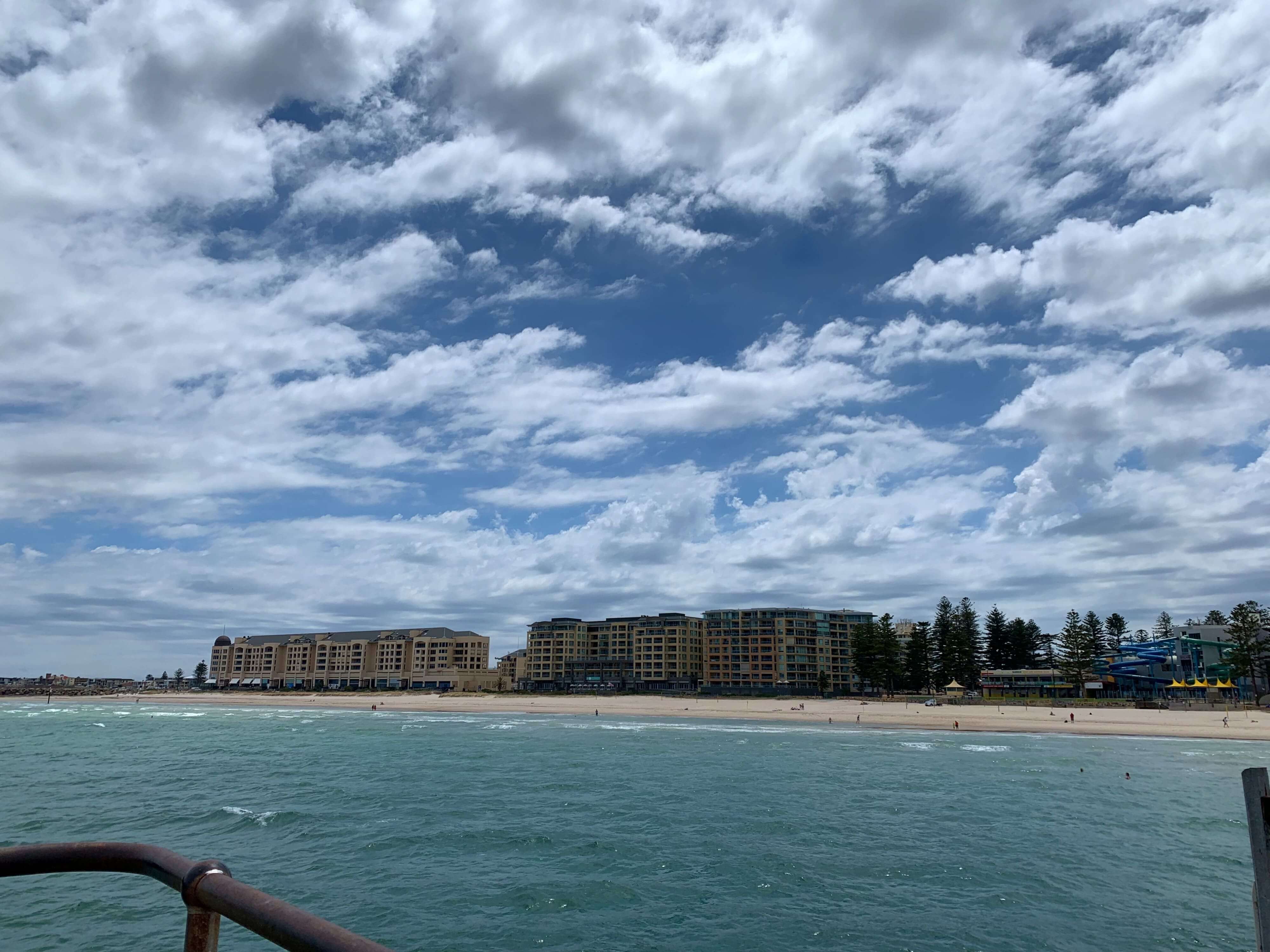 photo taken from the jetty looking at the shore and an apartment building in the distance - Glenelg beach in Adelaide