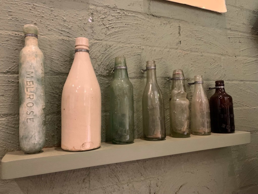 Photo of seven vintage beer bottles from the Melrose museum. 