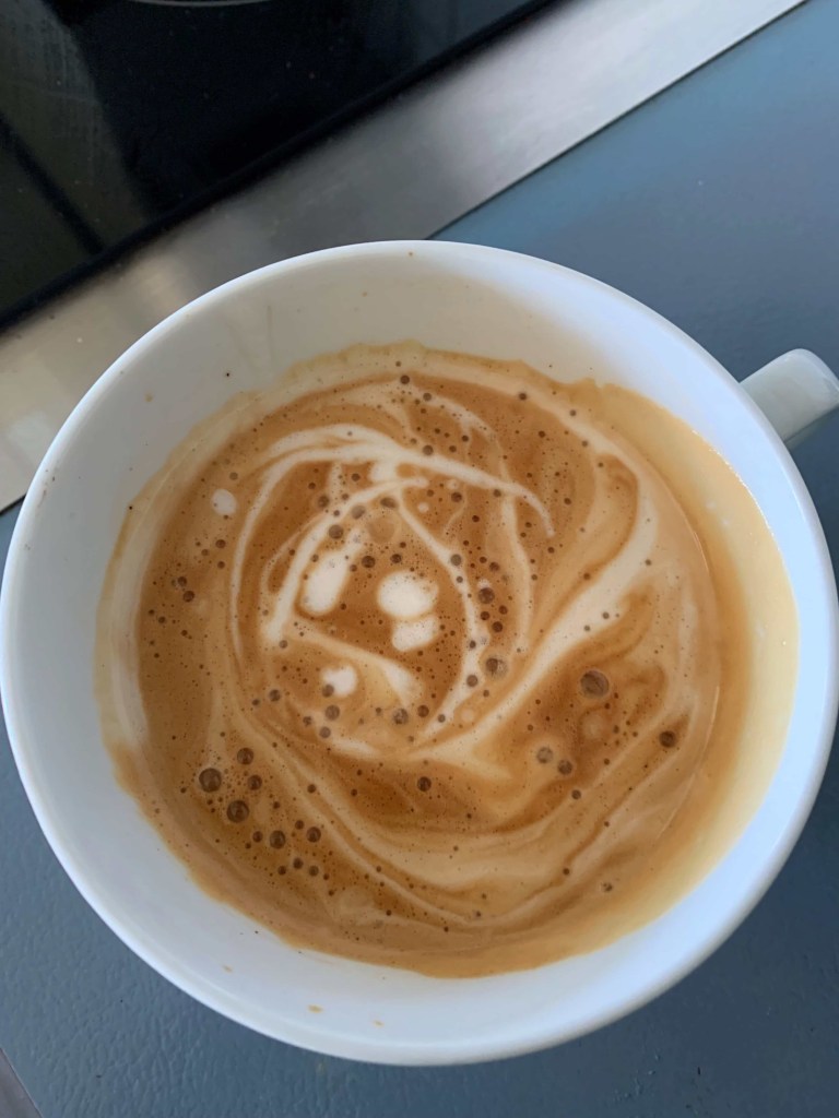 Close up photo of a barista style coffee in a wide white cup. 
