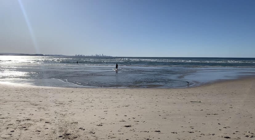 Photo of a person walking into the sea, on a sunny day at the beach. 