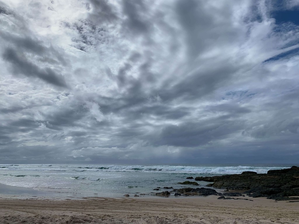 Photo of heavy, dark clouds on a beach, in a swirling motion.