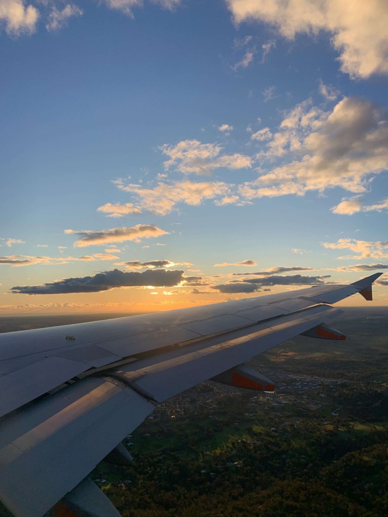 Photo of the sunset over the wing of a plane, as seen from the window seat. 