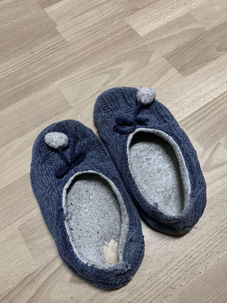 Photo of a pair of leg warmers, one with a big hole where the heel should be. 