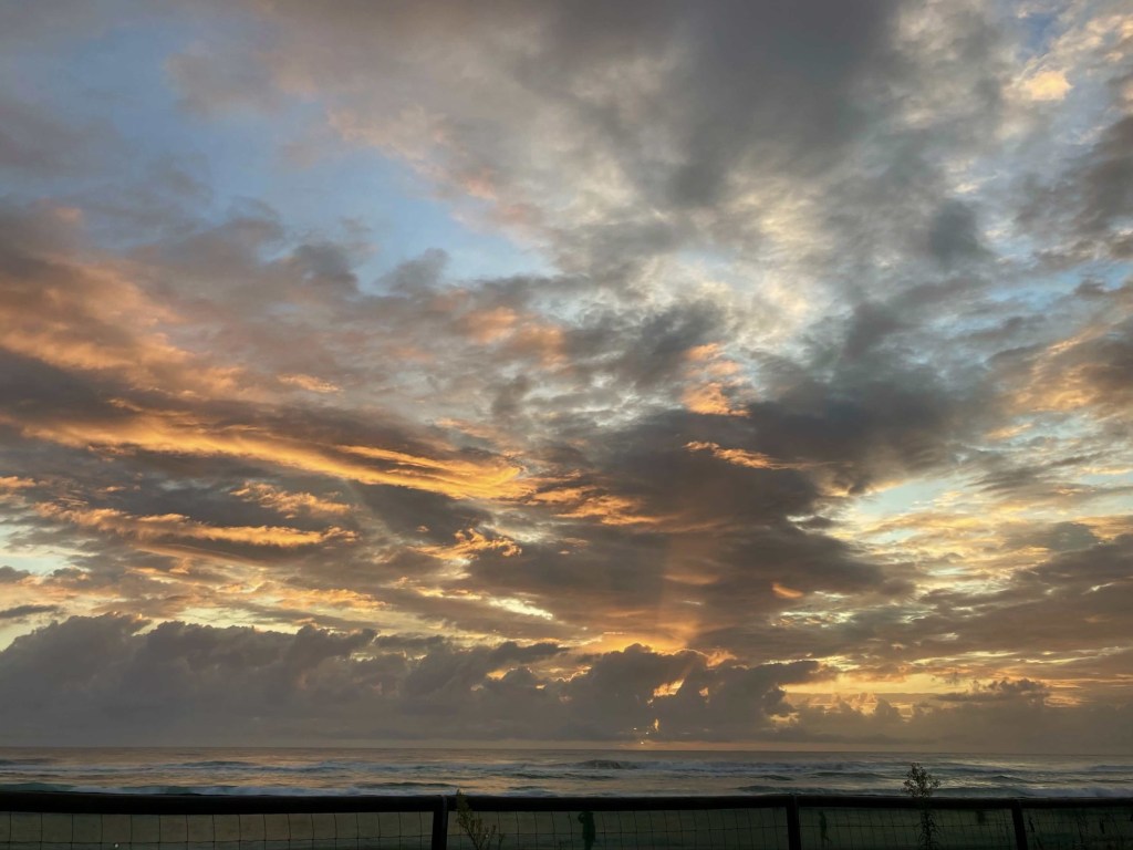 Photo of the sun rising from behind the clouds. 