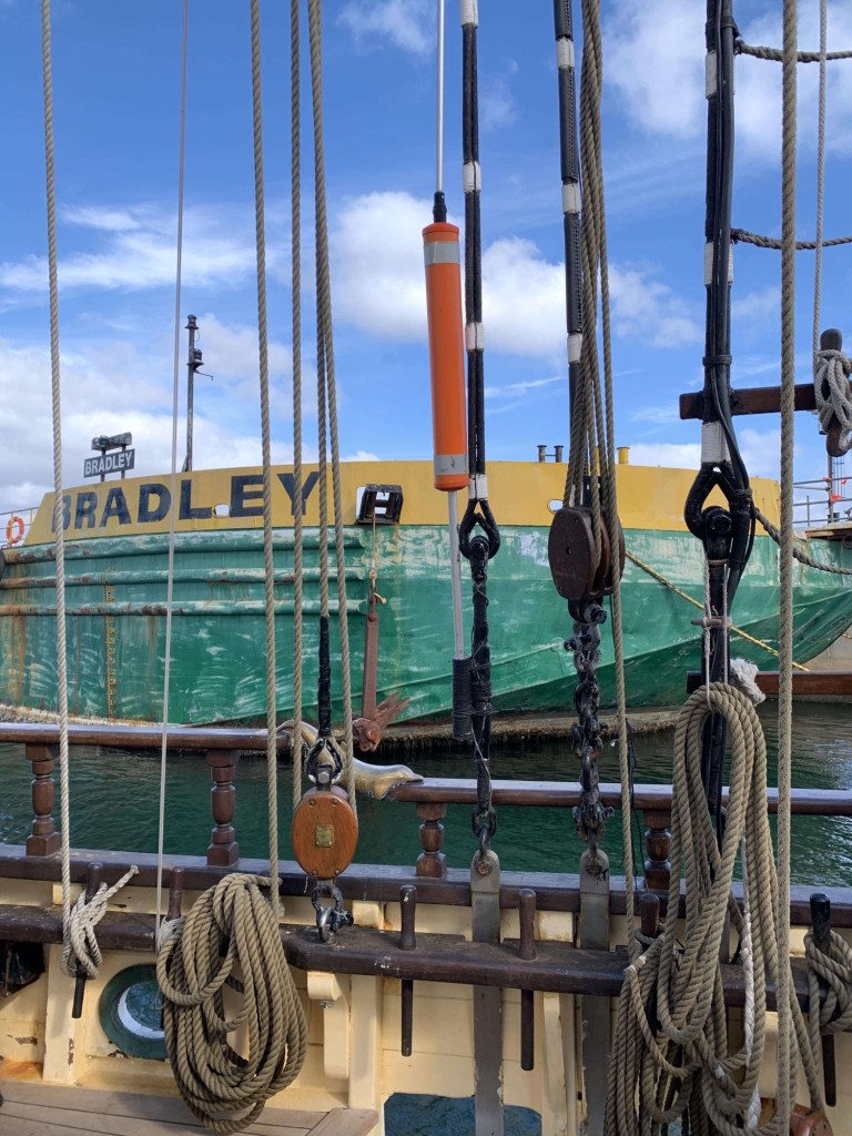 Photo of the port side of a tall ship with the ropes alongside it. 