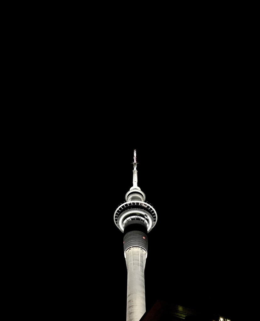 Photo of the Sky Tower in Auckland lit up against a dark sky. 