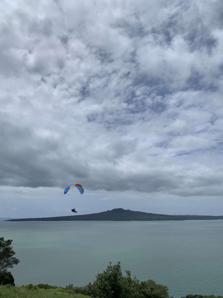 Photo of a windsurfer with Rangitoto Island in the background. 