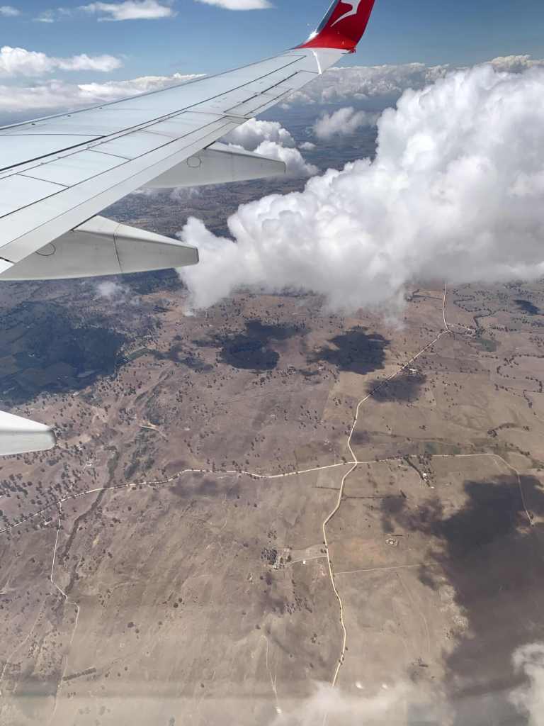 photo of white clouds under a plane's wing, as seen from the window of the plane