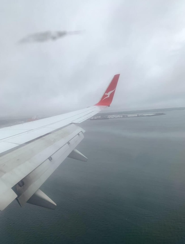 Photo of a plane’s wing, flying through mild fog, as seen through the plane’s window. 