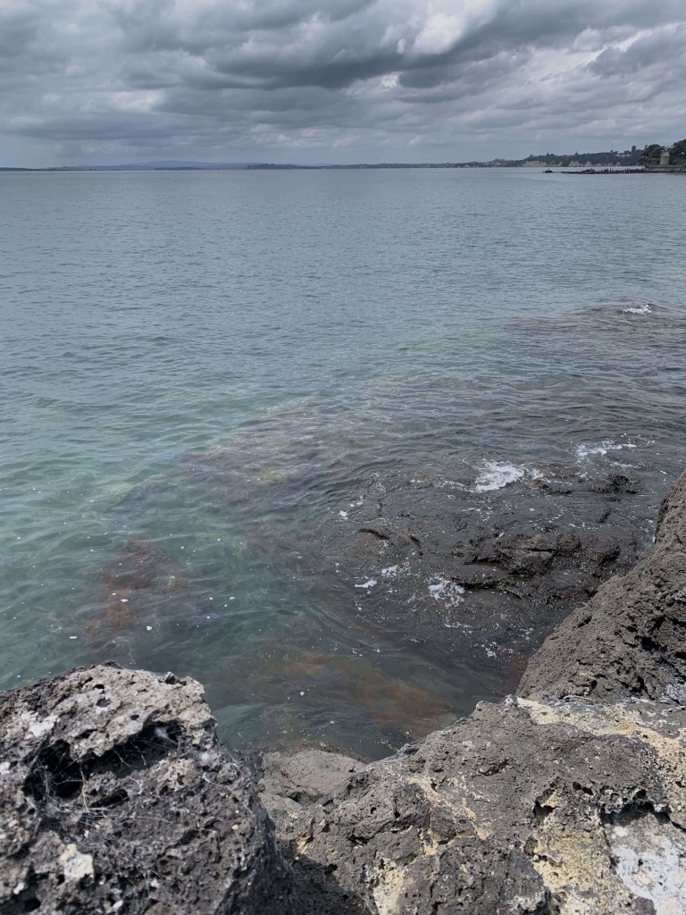 Photo of ocean lapping on the rocks by the shore. 