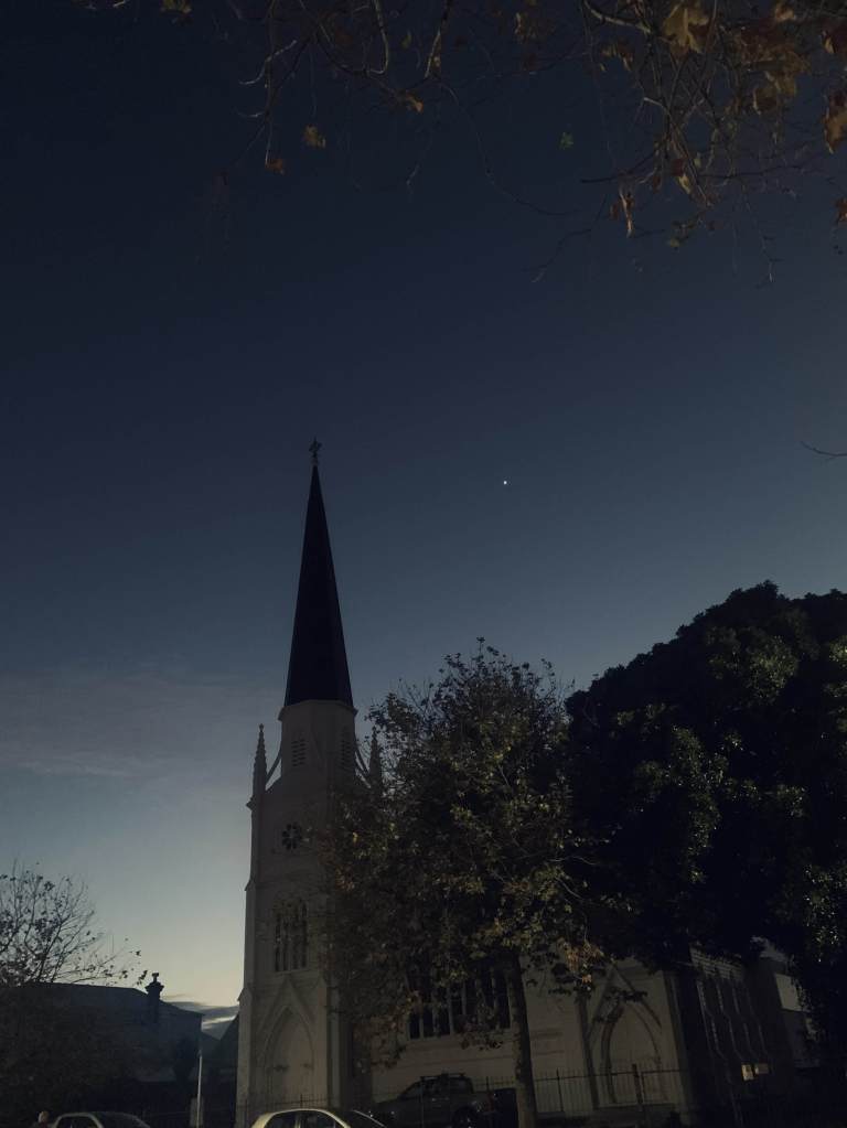 photo of a tall church, just before sunrise