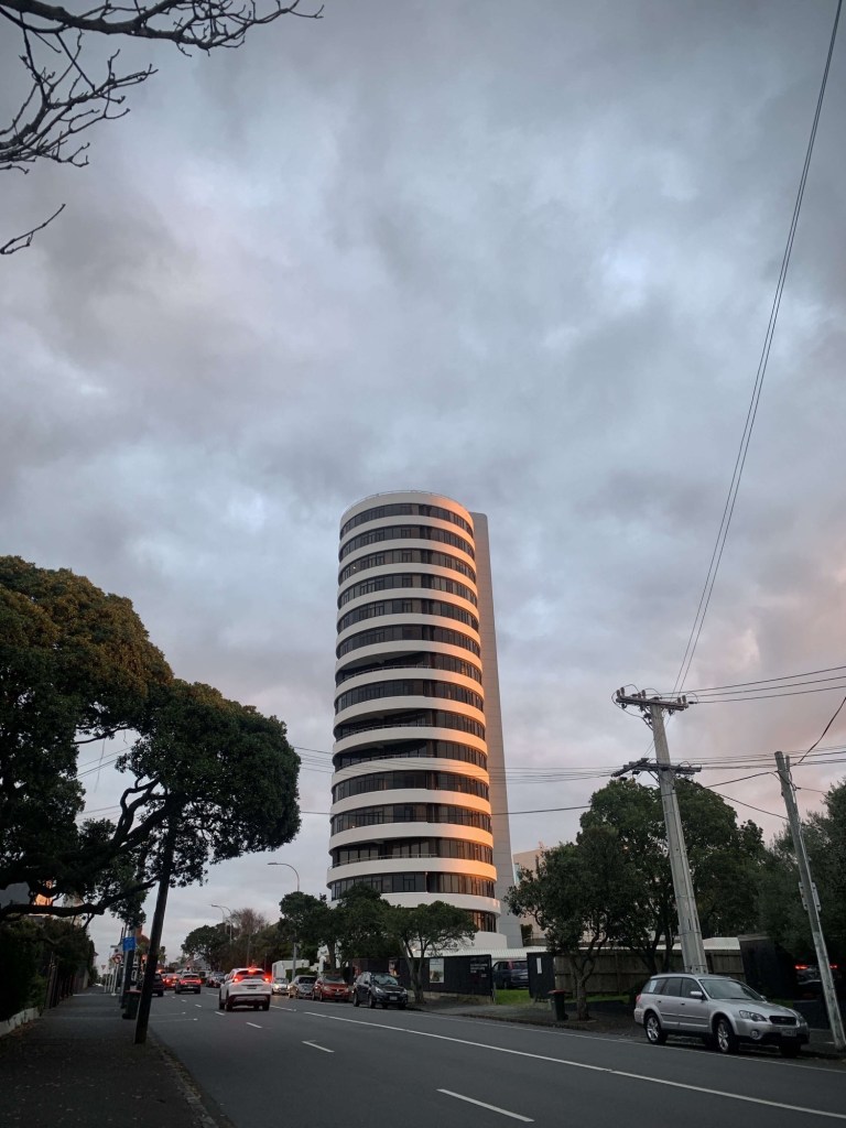 Photo of a high rise building with the setting sun’s light reflecting on it. 