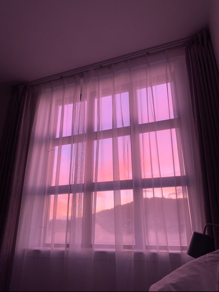 Ok hoot do the pink-orange glow of the predawn, as seen through the light curtains of a bedroom window. 